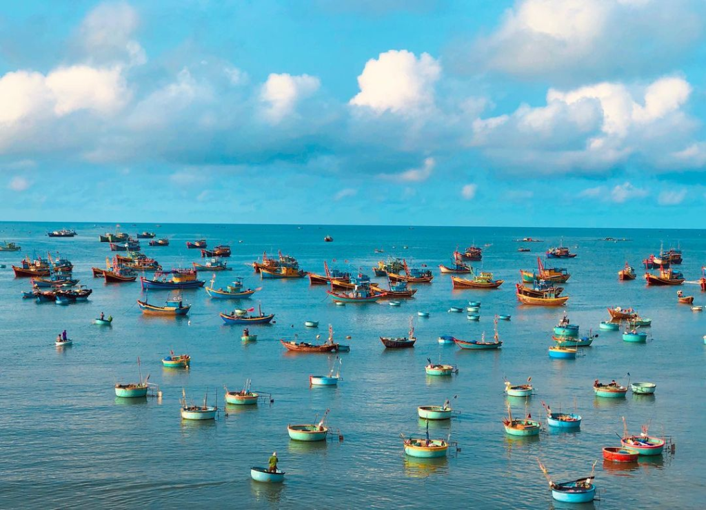 Cảnh biển Phan Thiết thơ mộng với bầu trời trong xanh và những tàu thuyền nhộn nhịp.